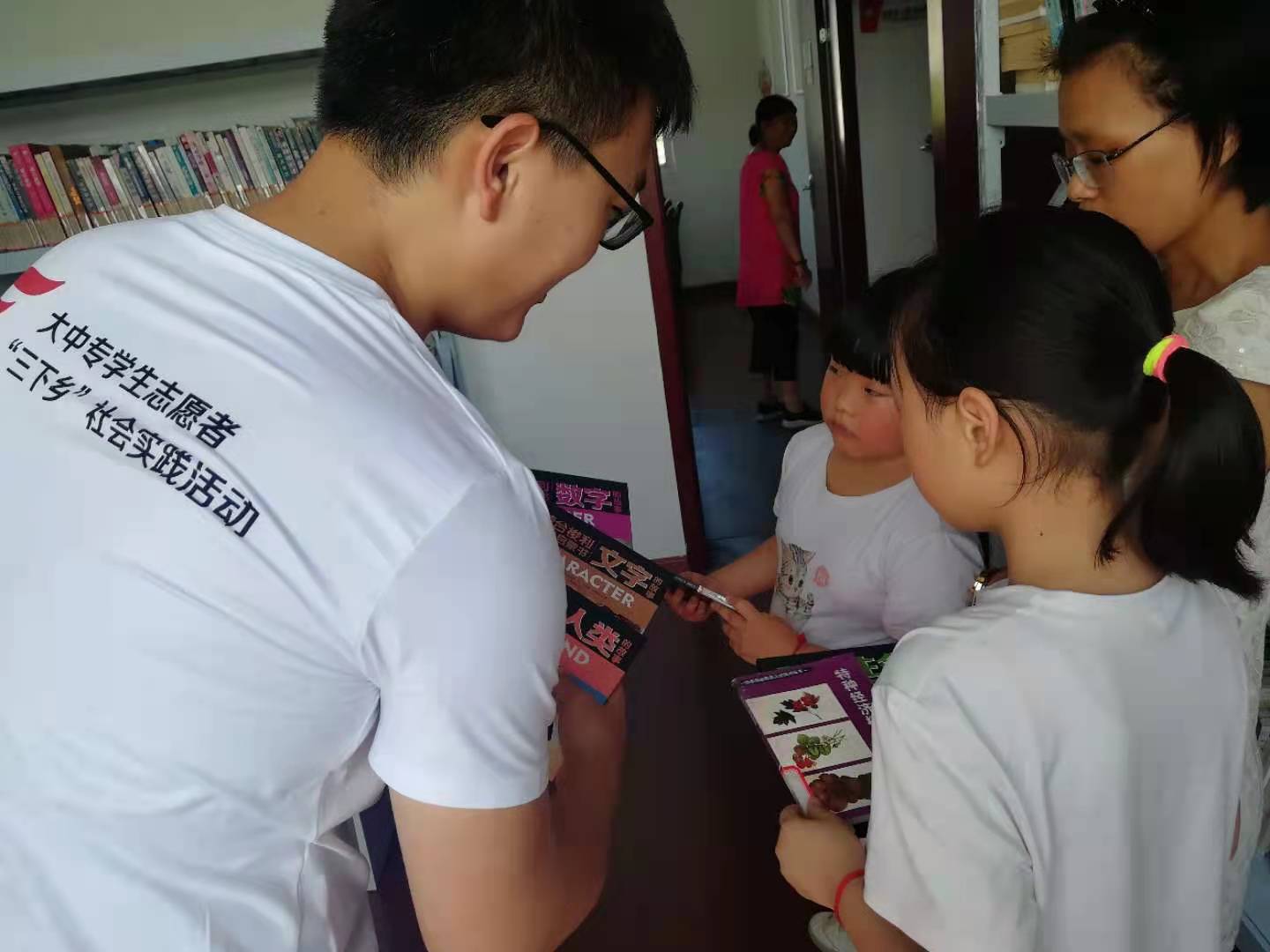 图为团队成员向小朋友赠送书籍.jpg
